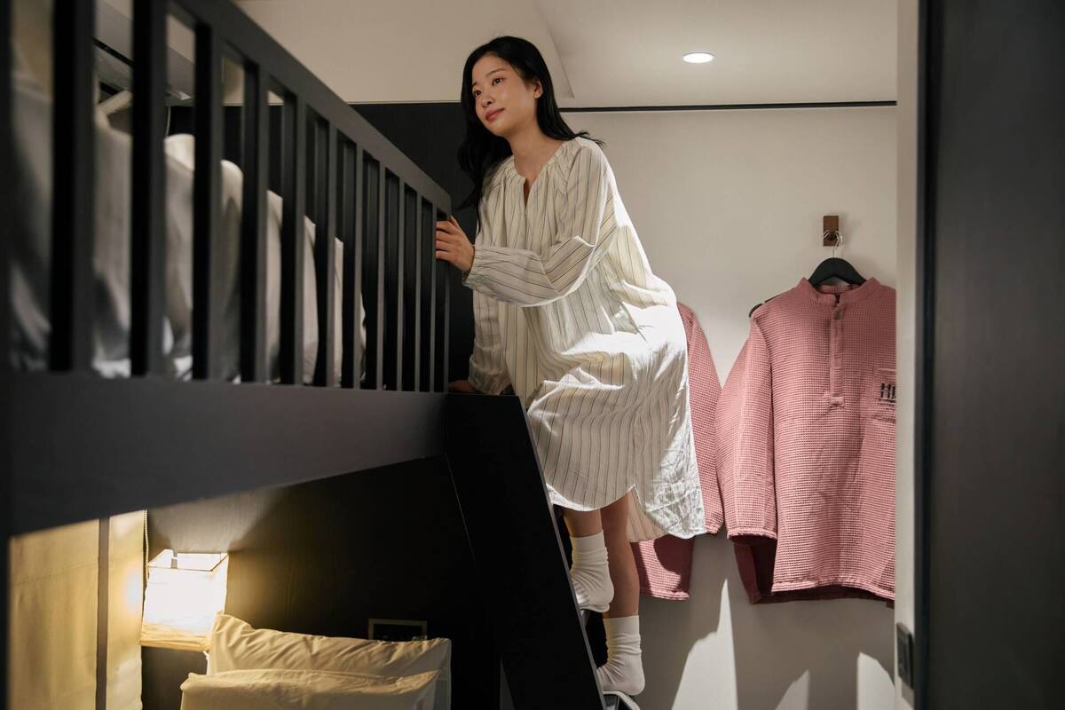 Eine Person steht auf einer Treppe in einem Zimmer mit einem Bett und einem Schrank.