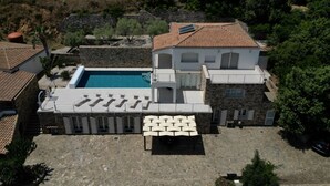 En villa med en swimmingpool, utomhusmöbler och en terrass i sten.