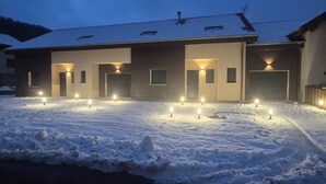 Lumipeitteinen rakennus, jossa on useita valaistuja sisäänkäyntejä ja lumipeitteinen maa.