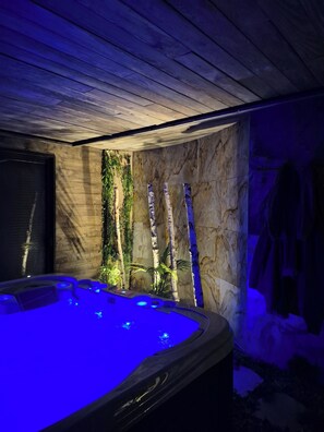 Area benessere con vasca idromassaggio, soffitto in legno e parete con giardino verticale.
