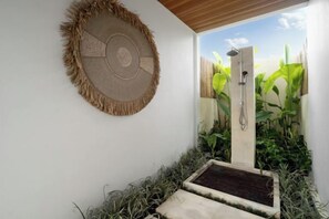 Une salle de bain avec une douche, un porte-serviettes fixé au mur et un petit marchepied menant à l’espace douche.