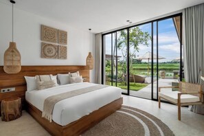 Une chambre avec un grand lit, une tête de lit en bois, une vue à travers des portes vitrées et un fauteuil en osier.