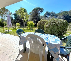 Un patio al aire libre con mesa y sillas, rodeado de follaje y árboles.