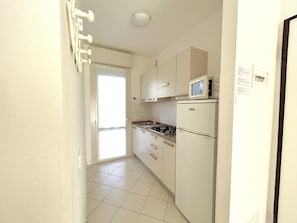 Una cocina con armarios blancos, un microondas, una estufa y un refrigerador.
