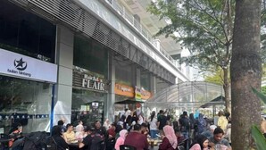 A crowded outdoor dining area with tables and chairs, a large glass storefront, and a sign for 'Hair Salon FLAT'. - The CEO Suite7 by Homey Planet (Bayan Lepas)