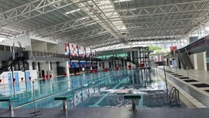 An indoor swimming pool with multiple lanes, a diving platform, and a covered roof structure. - The CEO Suite7 by Homey Planet (Bayan Lepas)