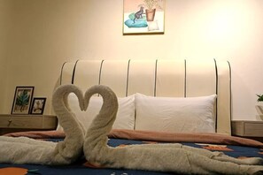 A bed with a heart-shaped towel arrangement, a bedside table with a lamp, and a wall-mounted picture. - The CEO Suite7 by Homey Planet (Bayan Lepas)