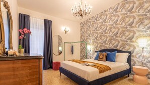Une chambre à coucher avec un grand lit, une commode, un miroir, un lustre et un mur orné d’un motif.