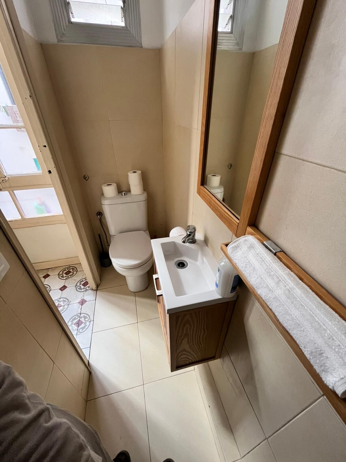 A compact bathroom with a toilet, sink, and mirror.