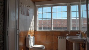Een badkamer met toilet, wastafel en raam.