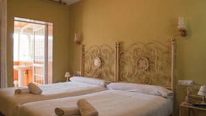 Een hotelkamer met twee bedden, een badkamer zichtbaar door een open deur en een nachtkastje met een lamp.
