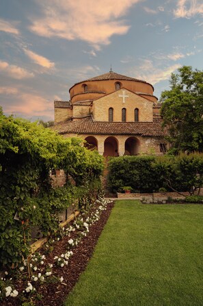 A historic building with a cross, arched windows, and a circular roof. - Locanda Cipriani Torcello (Torcello)
