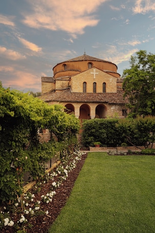 A historic building with a cross, arched windows, and a circular roof.