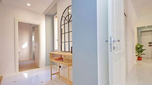 Un pasillo con un banco de madera, una ventana de metal y una planta en maceta.
