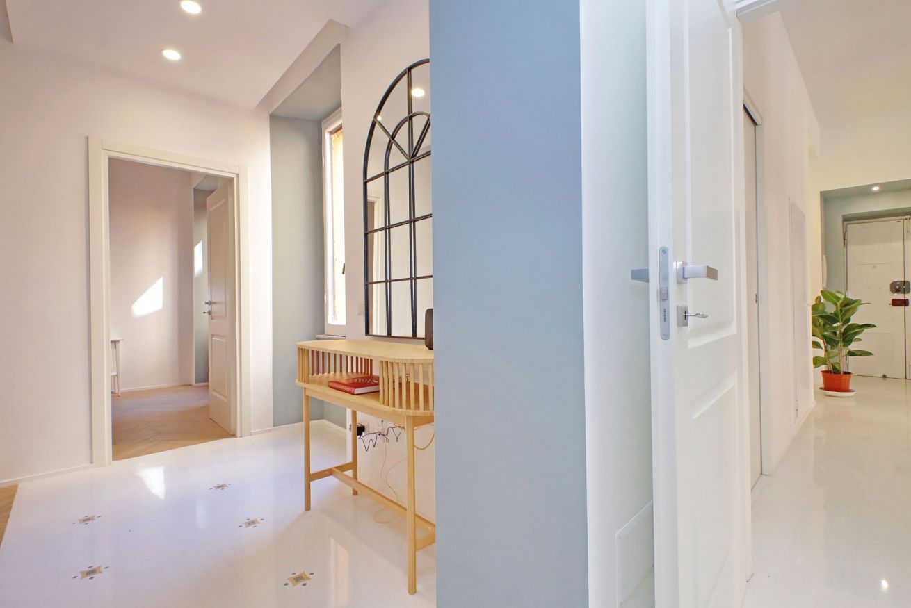 A hallway with a wooden bench, a metal-framed window, and a potted plant.