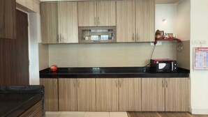 A modern kitchen with wooden cabinets, a black countertop, and a microwave. - LONAVALA TURGARLI-ESCAPE TO BYGONE ERAA HOME WITH SOUL (Lonavala)