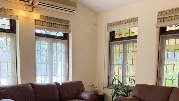 A living room with two brown leather sofas, a round wooden coffee table, and a potted plant. - LONAVALA TURGARLI-ESCAPE TO BYGONE ERAA HOME WITH SOUL (Lonavala)