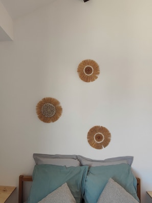 Une chambre à coucher avec un lit, des oreillers et trois éléments décoratifs fixés au mur.