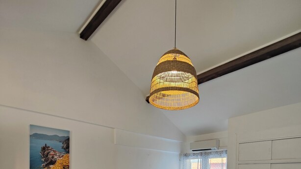 A modern living room with a dining table, sofa, and a hanging light fixture.