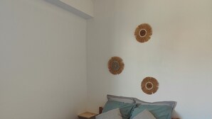 A single bed with a wooden frame, a blue and grey blanket, and two pillows. There are three wall-mounted decorative items.