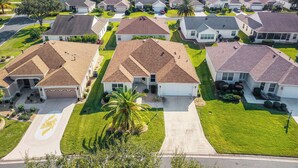 Um bairro residencial com casas de estilos arquitetônicos semelhantes, gramados bem cuidados e um campo de golfe ao fundo.