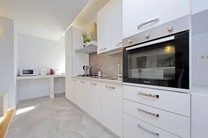 A modern kitchen with white cabinetry, a built-in oven, and a microwave. - Stylish 3 bedrooms apartment near Vatican (Roma)