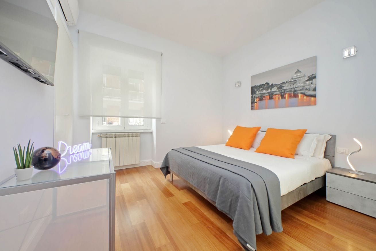 Un dormitorio moderno con cama, mesita de noche, una ventana y una obra de arte colgada en la pared.