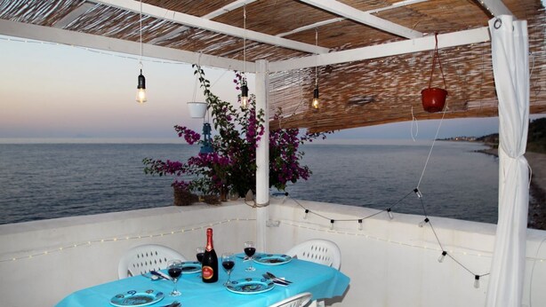 Een tafel voor twee met een fles wijn, glazen en borden, met uitzicht op zee.
