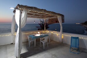An outdoor dining area with a table and chairs, a pergola with string lights, and a view of the sea. - The Casello sul Mare is a historic railway house built in 1895 as a residence for railway workers and restored in 2025 while preserving its authentic charm. The property is set in a truly unique location, nestled between the railway and the sea, offering (Torremuzza)