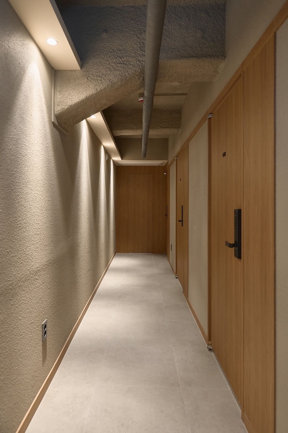 A narrow hallway with a wooden door on the right and a textured wall on the left.