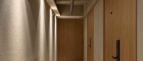 A narrow hallway with a wooden door on the right and a textured wall on the left.