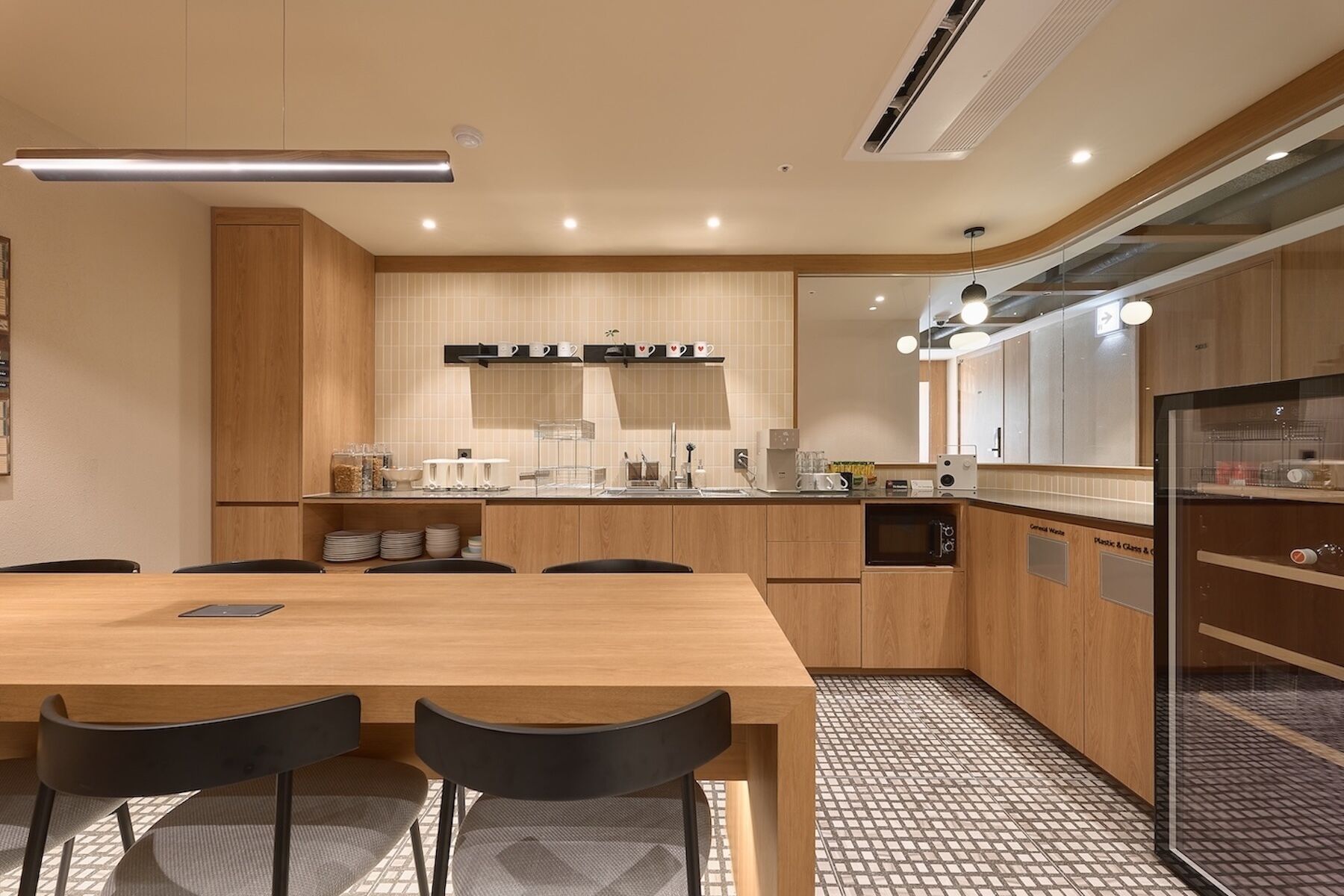 A modern kitchen with a wooden table and chairs, a built-in oven, and a refrigerator.