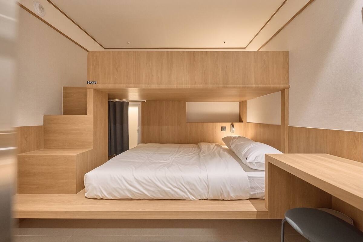 Een moderne slaapkamer met een houten stapelbed, een bureau en een stoel.