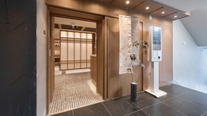 Een moderne hotelentree met een houten deur, een incheckautomaat en een betegelde vloer.