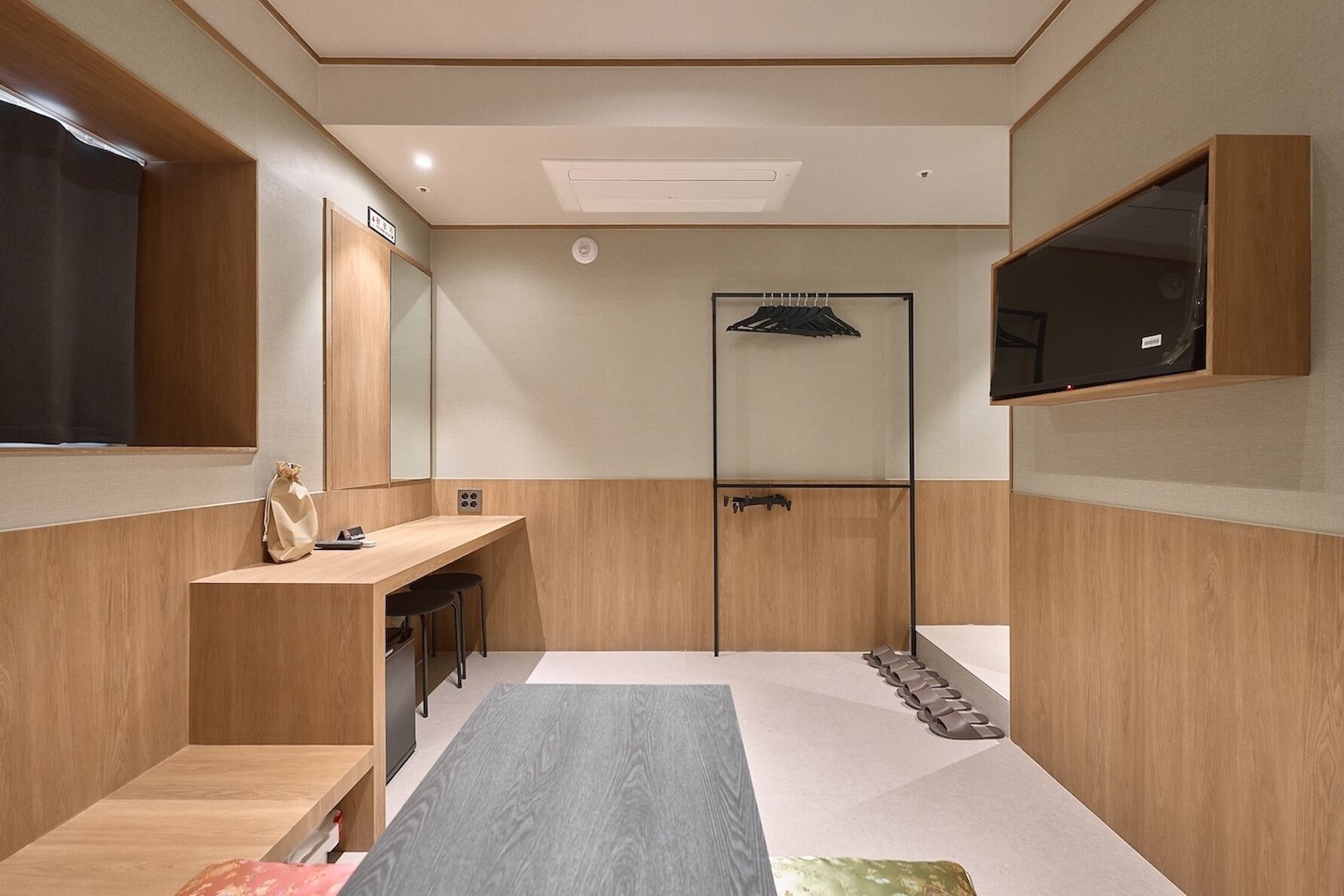 Ein modernes Badezimmer mit Waschtisch aus Holz, einem Spiegel, einer Duschkabine und einem integrierten Fernseher.
