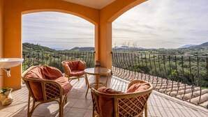 Ein Balkon mit Korbmöbeln und Blick auf eine gebirgige Landschaft.