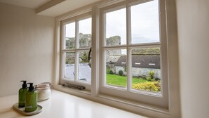 Une salle de bain avec une grande fenêtre, un lavabo et des articles de toilette.