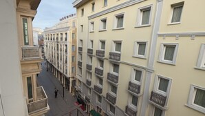 Una calle estrecha con edificios de varios pisos, balcones y una acera para peatones.
