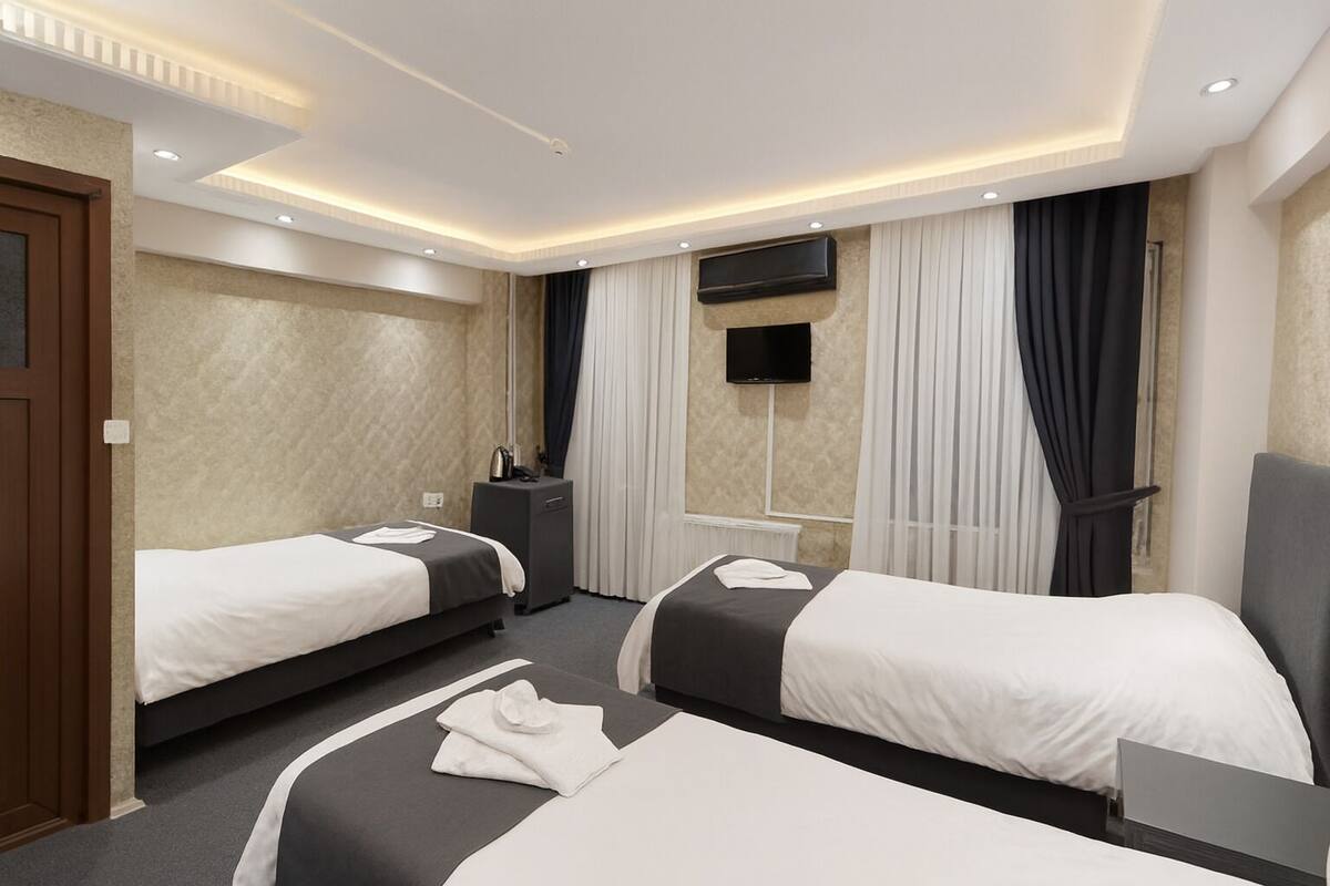 Una habitación de hotel con dos camas, un televisor de pantalla plana, un escritorio y un minibar.