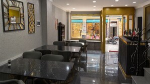 Un restaurante con mesas y sillas de mármol, una escalera y vistas a la calle.