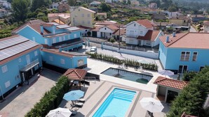 A residential area with a swimming pool surrounded by blue buildings, solar panels, and outdoor seating.