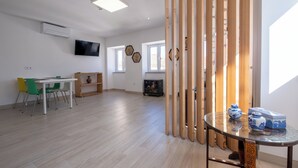 A spacious room with a dining table, chairs, a TV, and a decorative wooden partition.