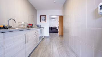 Eine moderne Küche mit integriertem Geschirrspüler, Spüle mit Armatur und Mikrowelle. An der Wand hängt ein gerahmtes Bild und eine Holztür führt in einen anderen Raum.