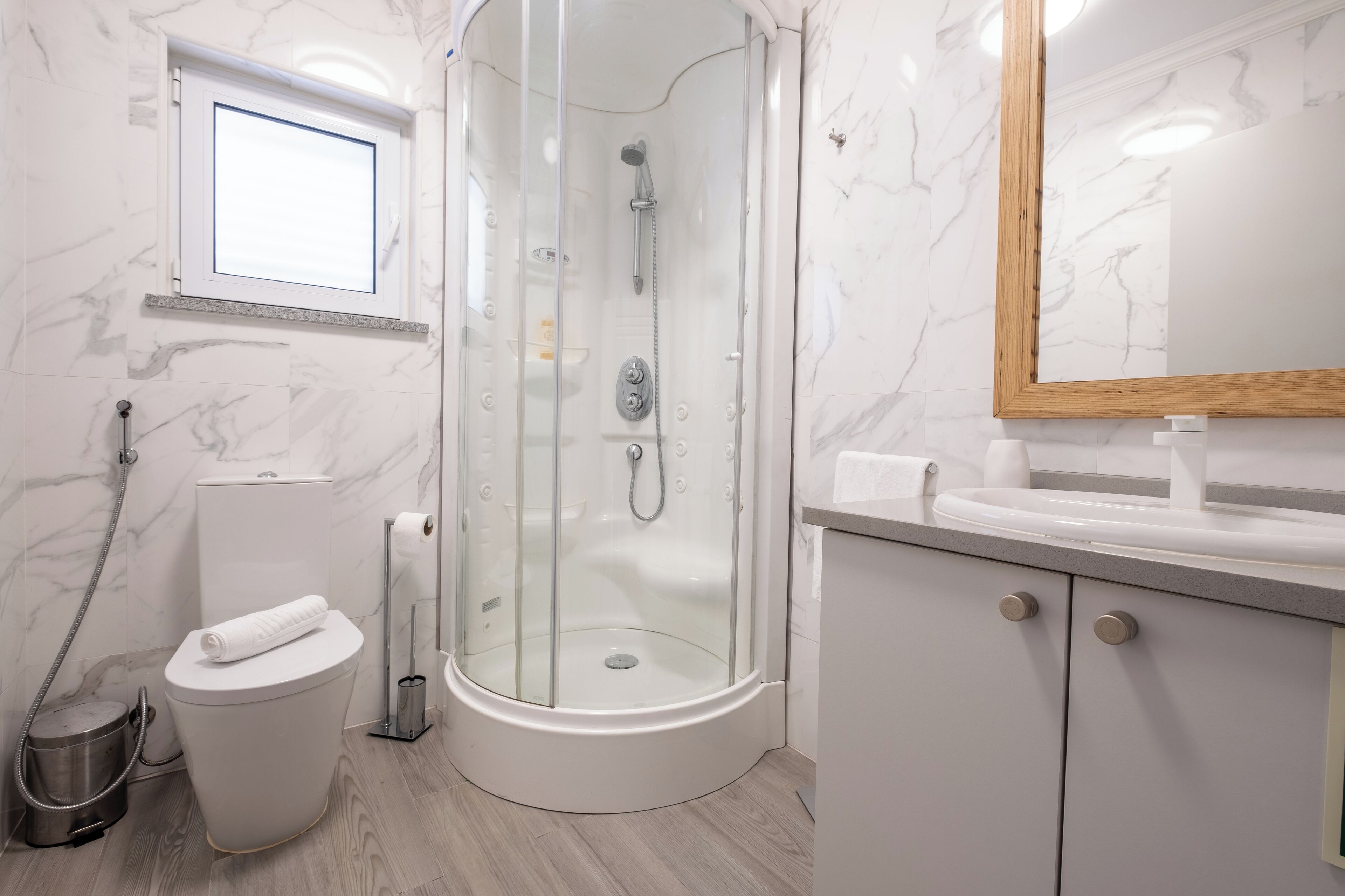 Une salle de bain moderne avec une douche à parois de verre, des toilettes, un lavabo et un miroir.