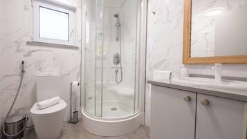 Une salle de bain moderne avec une douche à parois de verre, des toilettes, un lavabo et un miroir.