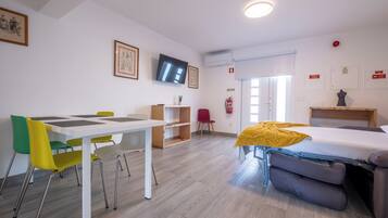 Ein Zimmer mit einem Bett, einem Tisch mit Stühlen, einem Fernseher und einem Feuerlöscher.
