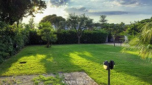 Ein gepflegter Garten mit Rasen, Bäumen und einem Kiesweg.