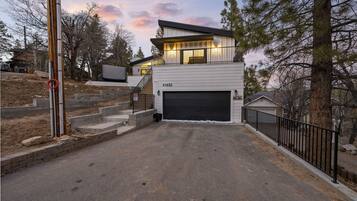 A modern two-story house with a garage, a staircase leading to the upper level, and a driveway.