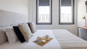 A neatly made bed with a breakfast tray, two windows with blinds, and a desk with a lamp. - Regras Apartments & Garden A14 by Benefit Collection (Porto)