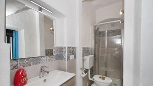 A bathroom with a white sink, a mirror, a toilet, and a shower enclosure. - The Casello sul Mare is a historic railway house built in 1895 as a residence for railway workers and restored in 2025 while preserving its authentic charm. The property is set in a truly unique position, suspended between the railway and the sea, offeri (Torremuzza)